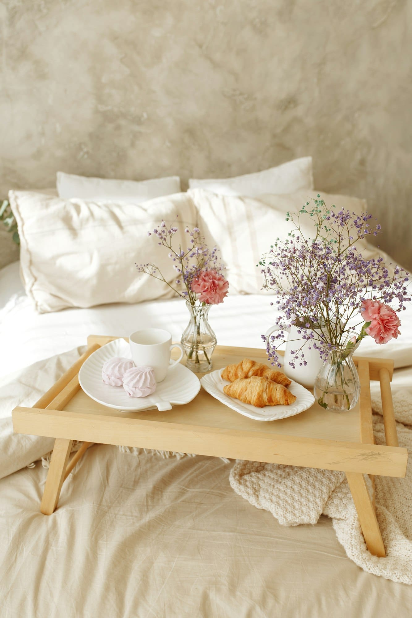 View of a wooden tray with breakfast in bed in a hotel room.